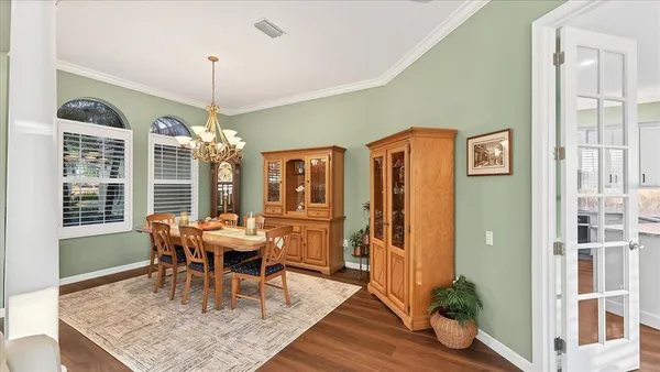 a dining room with furniture a chandelier and wooden floor