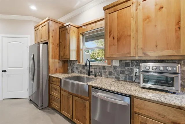 a kitchen with stainless steel appliances granite countertop a sink a refrigerator and a granite counter tops