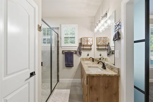 a bathroom with a granite countertop sink a mirror and shower