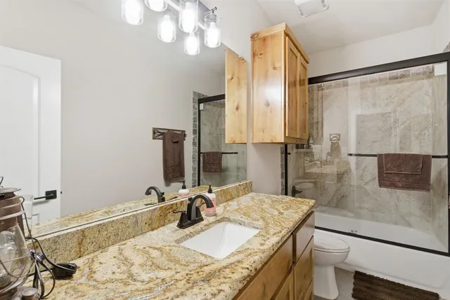a bathroom with a granite countertop sink a mirror and shower