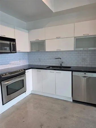 a kitchen with granite countertop white cabinets and stainless steel appliances