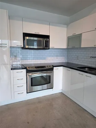 a kitchen with granite countertop white cabinets and stainless steel appliances