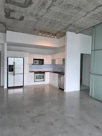 a view of an empty room with a kitchen