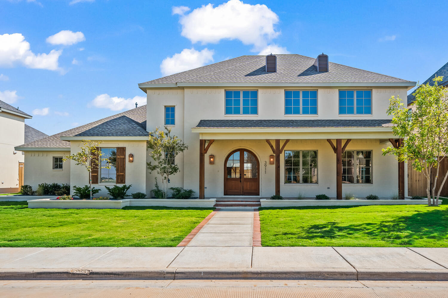 a front view of a house with a yard and potted plants