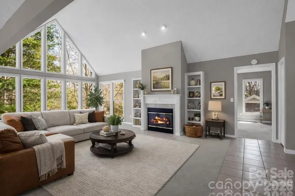 a view of a livingroom with a fireplace a chandelier and windows