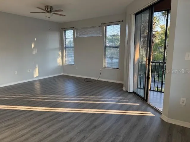 an empty room with wooden floor and windows