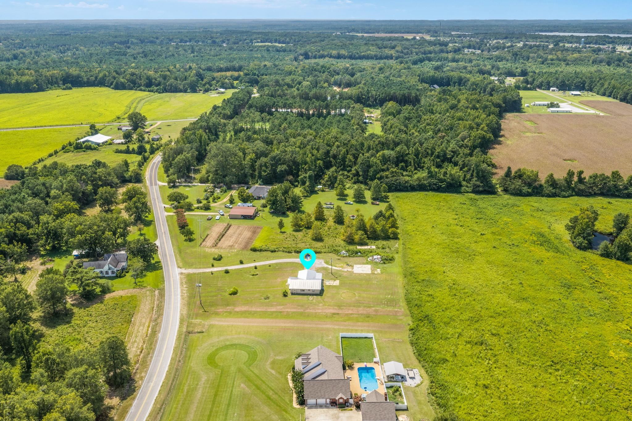 60116 Seminole Road Smithville, MS 38870 - Photo 33 of 38 Expansive green fields, substantial surrounding woodlands, paved road access, and scattered residential properties