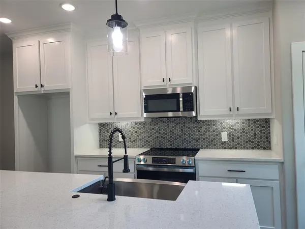 a kitchen with stainless steel appliances kitchen island granite countertop a sink a stove and a microwave