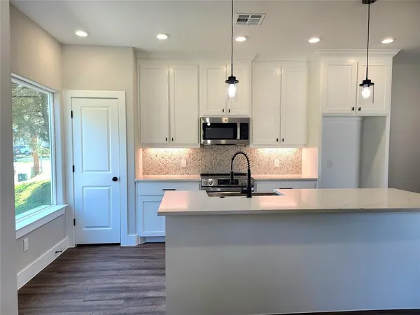 a kitchen with kitchen island a counter top space appliances and a window