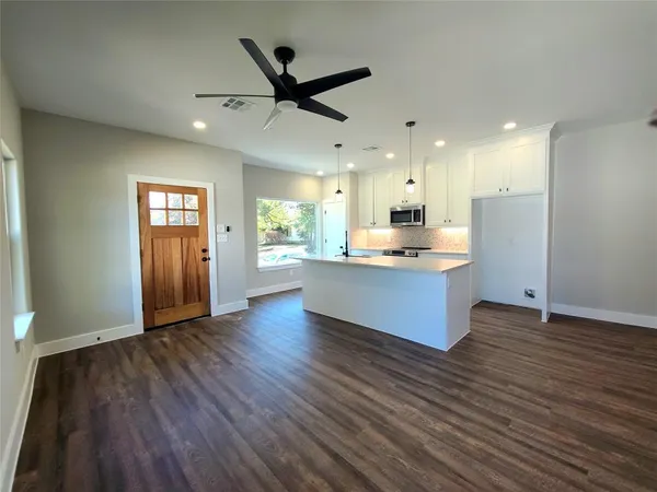 a large kitchen with a center island wooden floor stainless steel appliances and a window