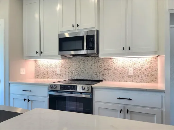 a kitchen with stainless steel appliances white cabinets and a stove top oven
