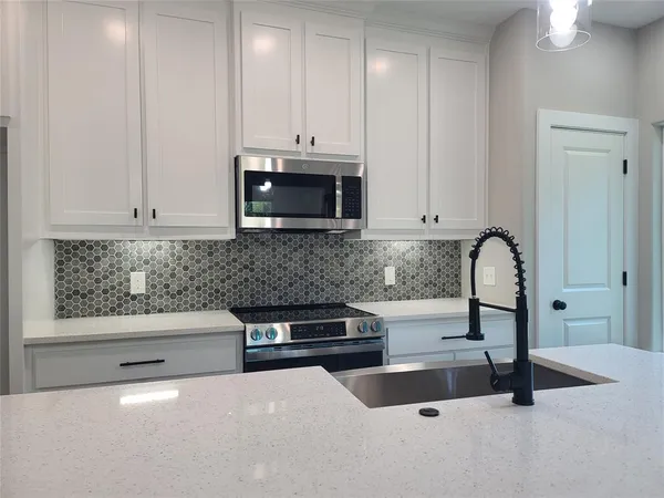 a kitchen with granite countertop a stove a sink and a microwave