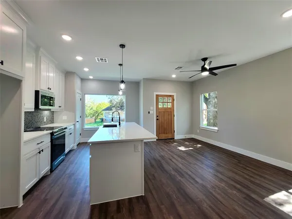 a kitchen with kitchen island a stove a sink and wooden floor