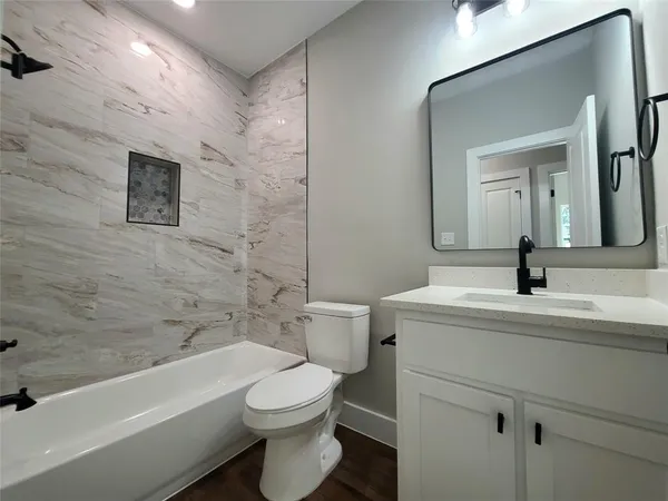 a bathroom with a toilet a sink a mirror and bathtub