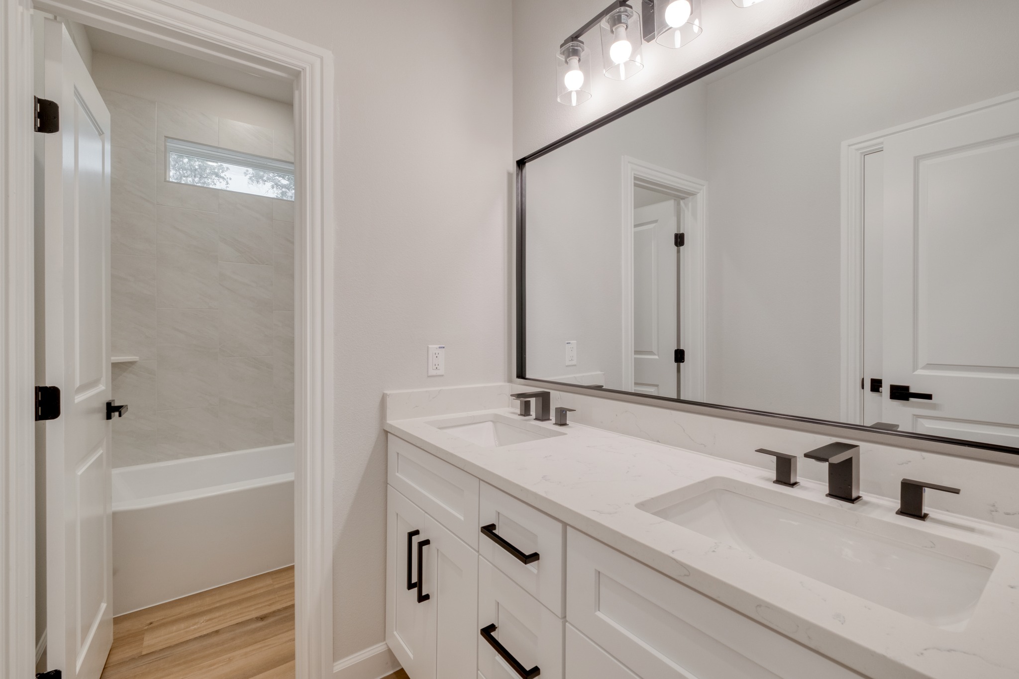 116 Pine Point Cove Elgin, TX 78621 - Photo 22 of 27 Dual vanity with white cabinetry and integrated sinks, complemented by matte black fixtures