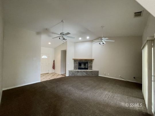 1133 West Benson Avenue Ridgecrest, CA 93555 - Photo 3 of 34 an empty room with a fireplace and fan