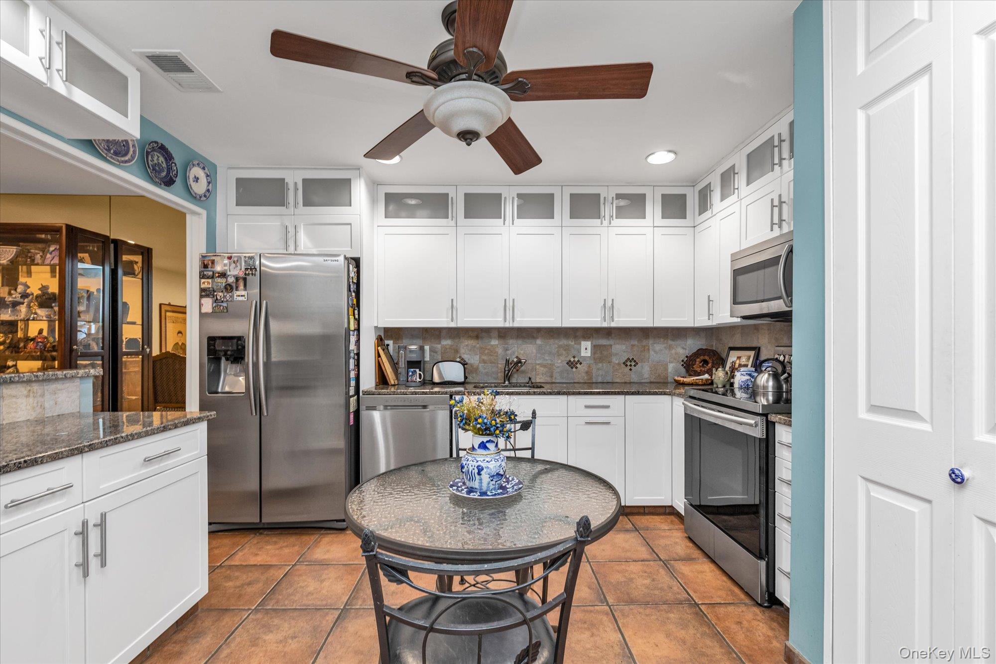 15 Spring Hollow Road Roslyn, NY 11576 - Photo 11 of 30 a kitchen with stainless steel appliances granite countertop a refrigerator a sink a stove and white cabinets