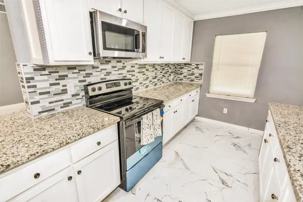 a kitchen with granite countertop a sink a stove and microwave