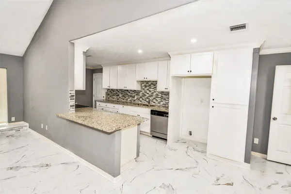 a kitchen with granite countertop a sink stove refrigerator and cabinets