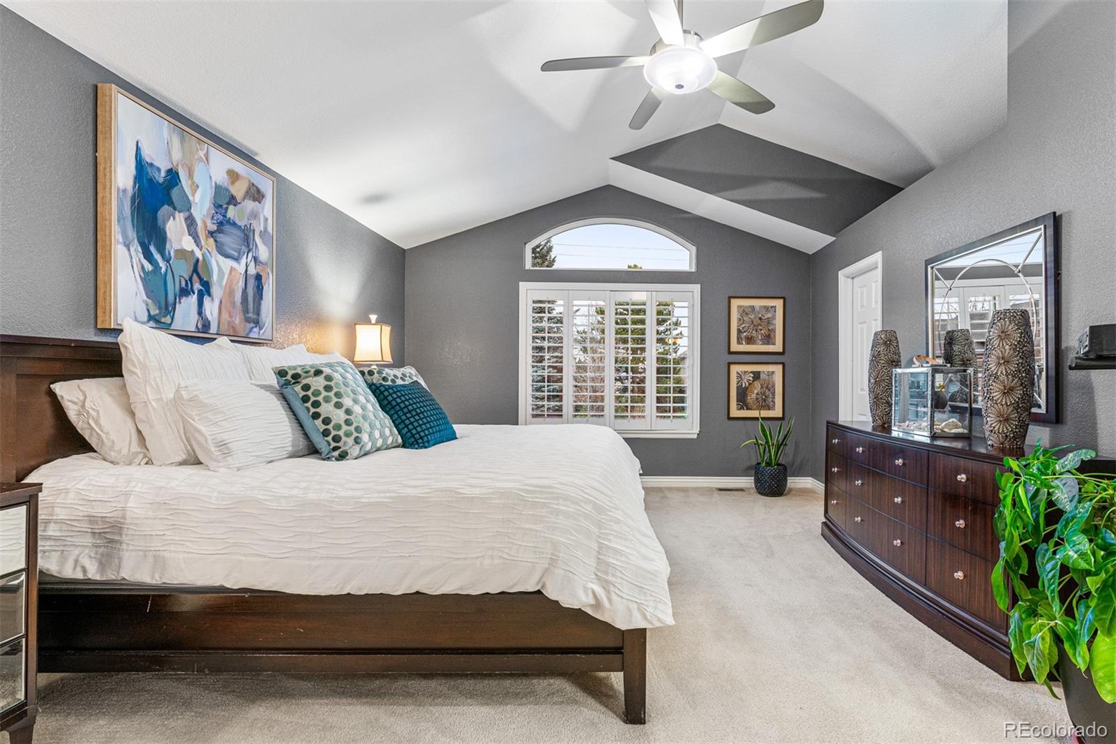 7340 Rattlesnake Drive Lone Tree, CO 80124 - Photo 19 of 33 a spacious bedroom with a large bed and a chandelier