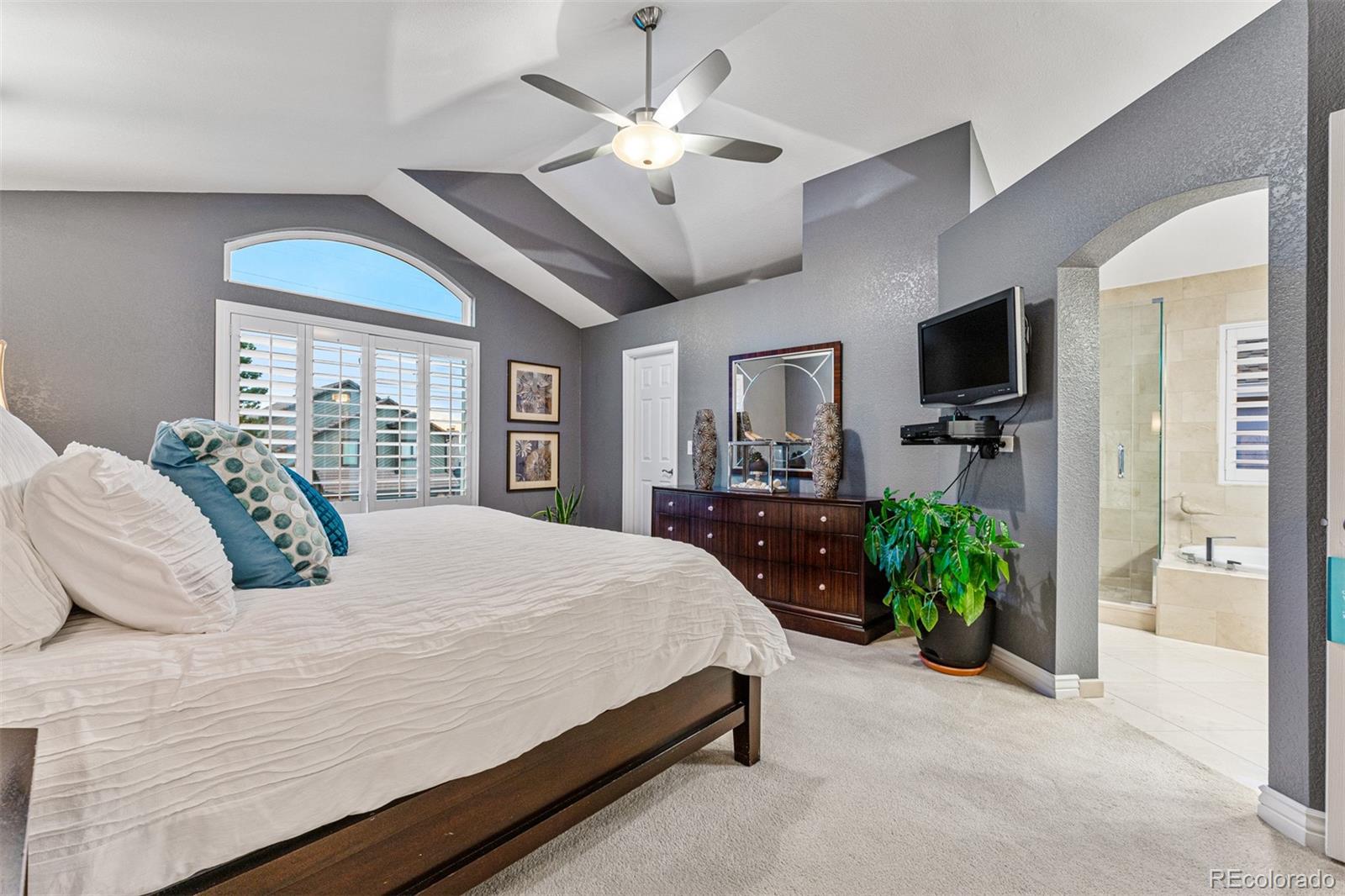 7340 Rattlesnake Drive Lone Tree, CO 80124 - Photo 20 of 33 a bedroom with a large bed a flat tv screen and a chandelier