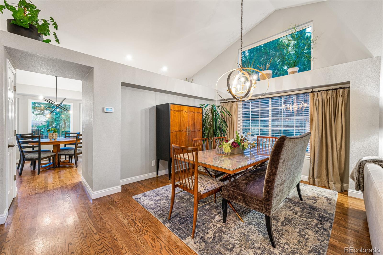 7340 Rattlesnake Drive Lone Tree, CO 80124 - Photo 7 of 33 a dining room with wooden floor a chandelier a wooden table and chairs