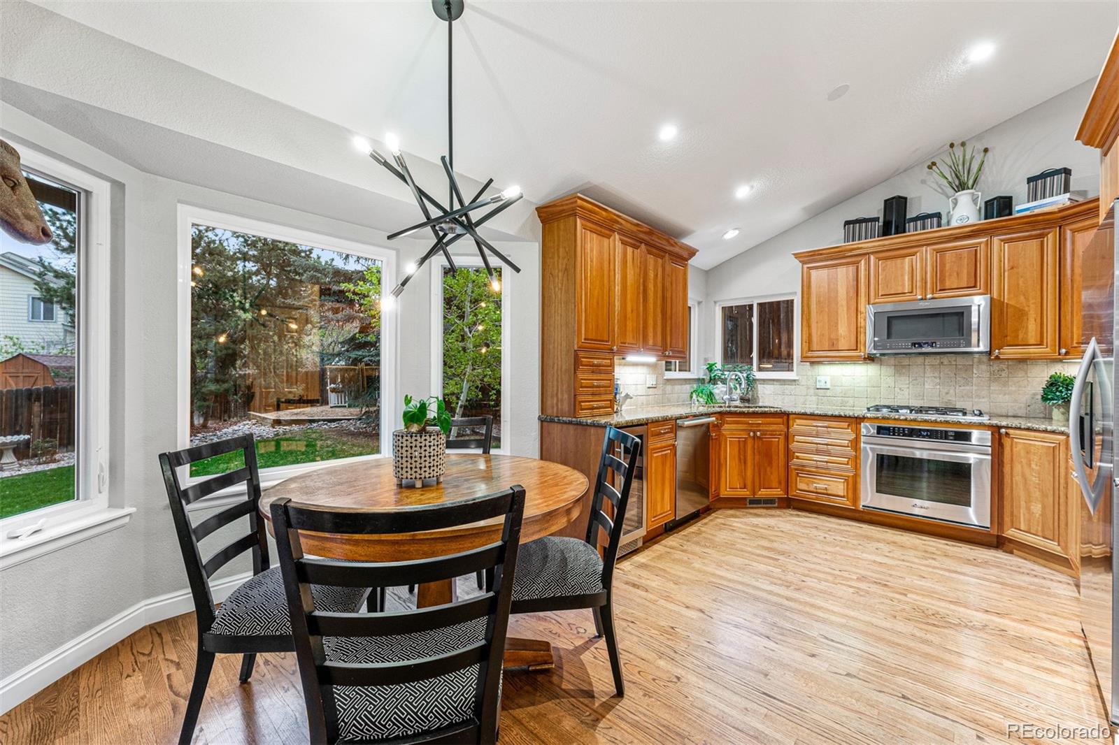 7340 Rattlesnake Drive Lone Tree, CO 80124 - Photo 8 of 33 a kitchen with stainless steel appliances granite countertop wooden floor dining table and chairs