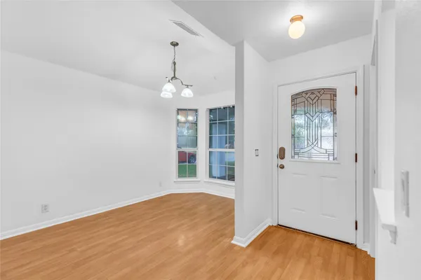 an empty room with wooden floor chandelier and windows