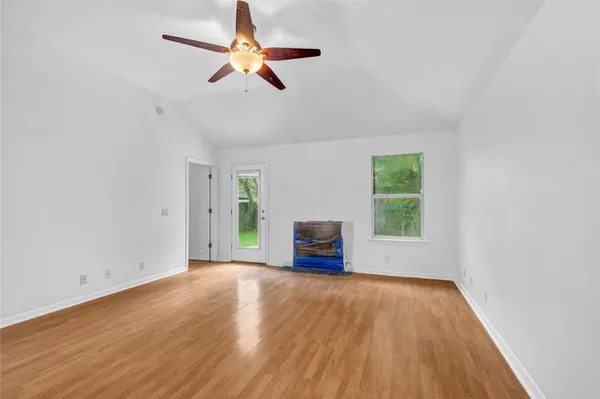 an empty room with wooden floor fan and windows