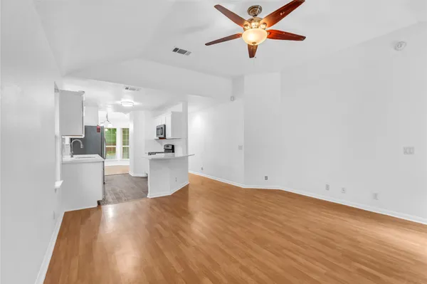 a view of kitchen and empty room with wooden floor