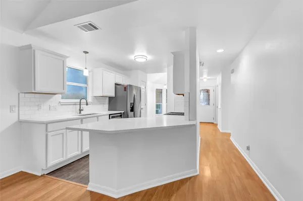 a large kitchen with stainless steel appliances granite countertop a sink a stove a refrigerator and white cabinets