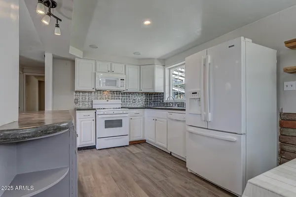 a kitchen with stainless steel appliances white cabinets and wooden floors