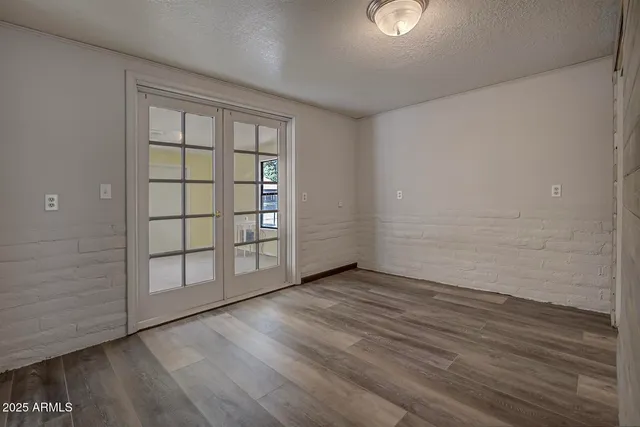 an empty room with wooden floor fireplace and windows