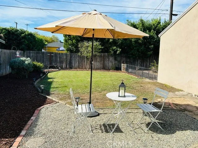 a backyard of a house with table and chairs under an umbrella