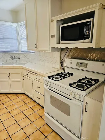 a kitchen with white cabinets and appliances