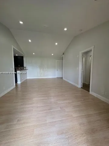 a view of empty room with wooden floor and a flat screen tv