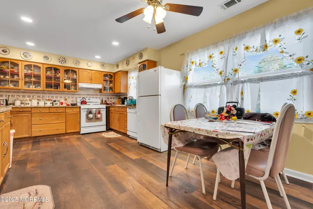 a kitchen with stainless steel appliances kitchen island granite countertop a table chairs sink and cabinets