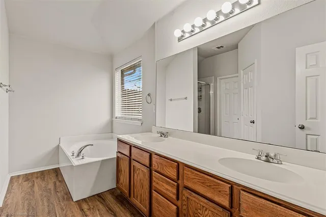 a spacious bathroom with a double vanity sink a mirror and a bathtub