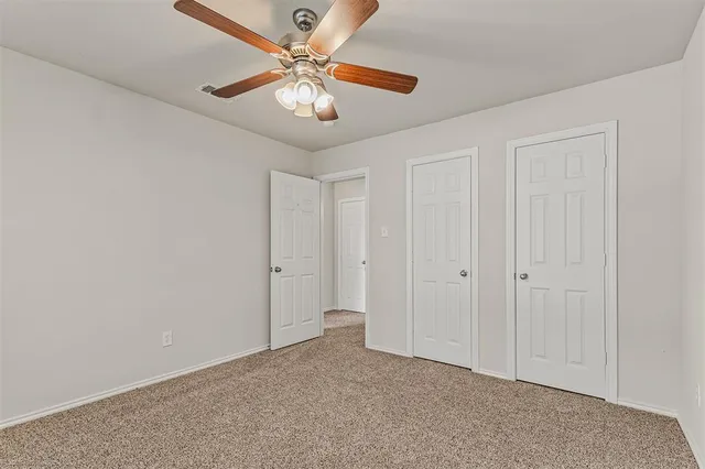 an empty room with a chandelier fan and windows