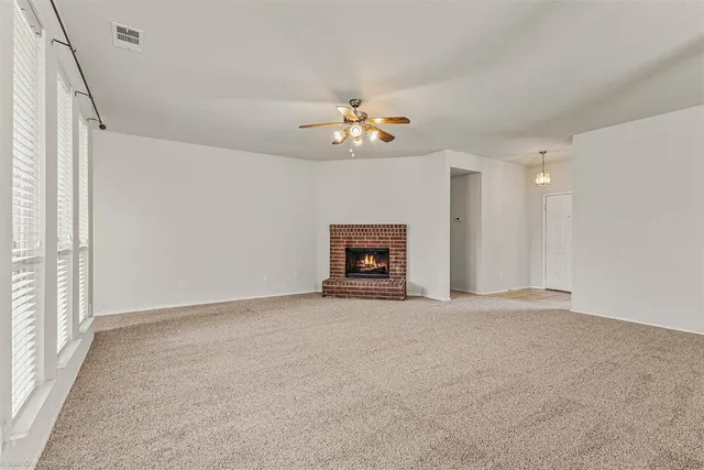 an empty room with windows and a ceiling fan