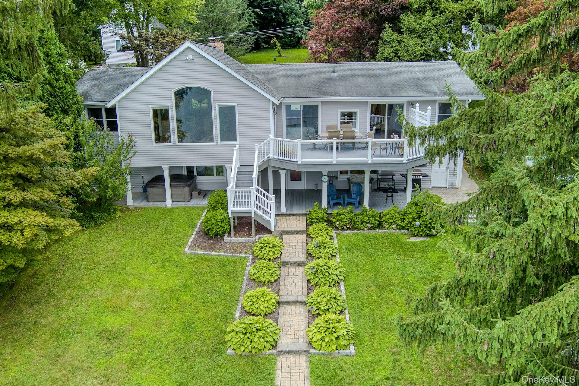 The stunning rear of the home showcases beautiful outdoor living spaces and multiple levels with breathtaking lake views. Lawns for badminton and bocce, a few steps from the lake.