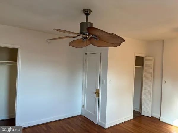 a view of a room with wooden floor ceiling fan and a window