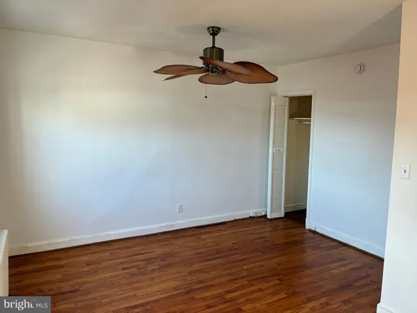 a view of empty room with wooden floor and fan
