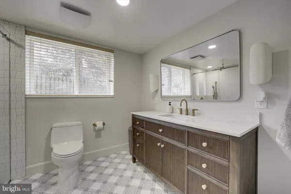 a spacious bathroom with a granite countertop sink a toilet and a mirror
