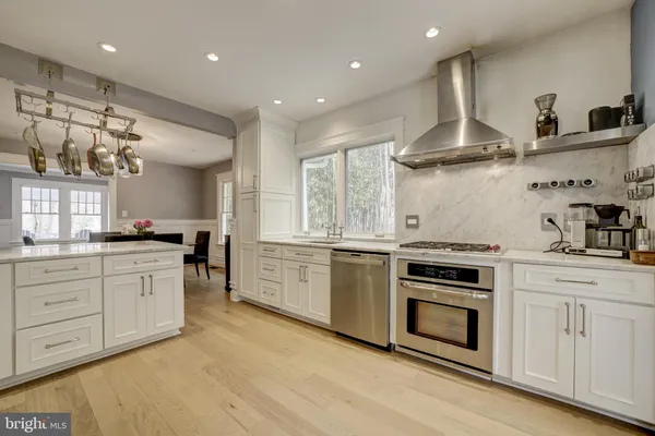 a kitchen with stainless steel appliances granite countertop a stove a sink and white cabinets