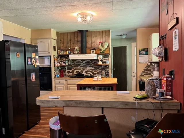 a kitchen with kitchen island a counter top space a refrigerator and cabinets