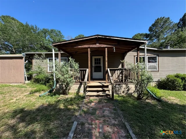 a view of a wooden house with a yard and potted plants