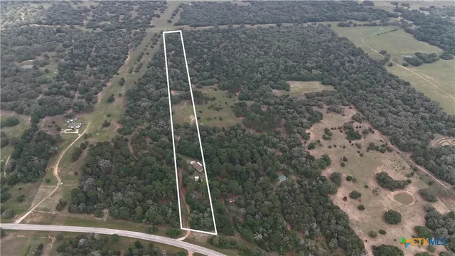 an aerial view of residential house with outdoor space and trees all around