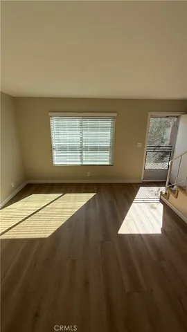a view of an empty room with wooden floor and door