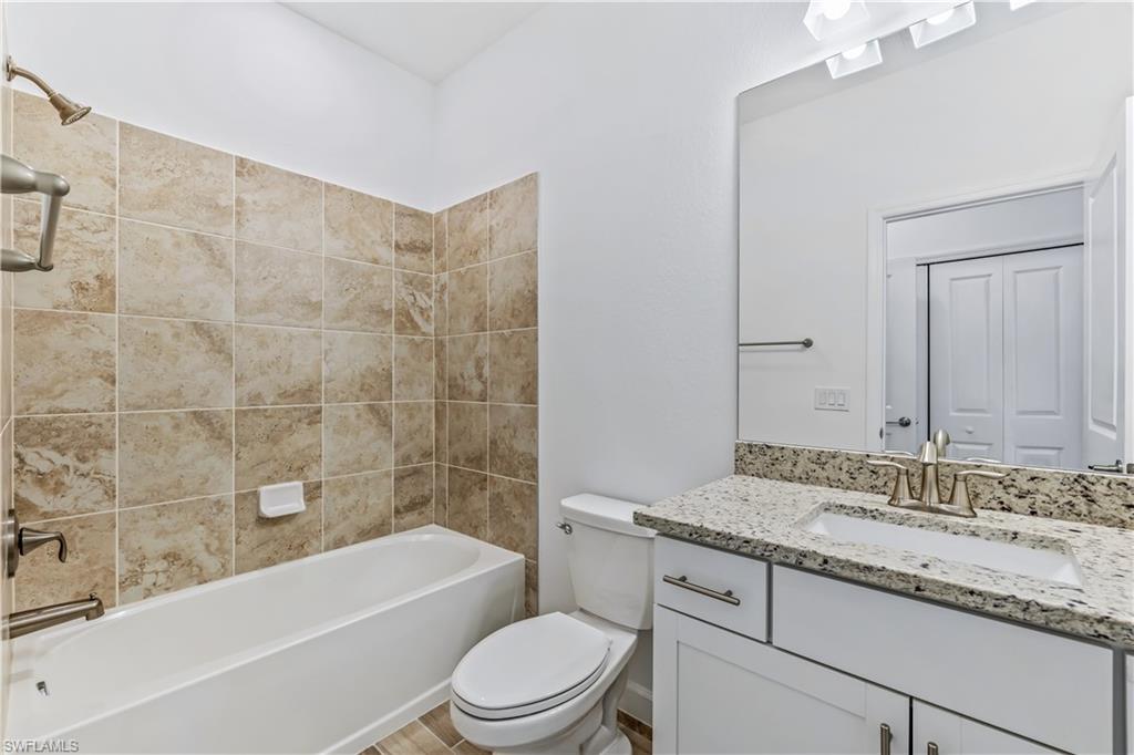 1817 Lema Court Naples, FL 34120 - Photo 22 of 22 a bathroom with a granite countertop bathtub shower sink vanity mirror and toilet